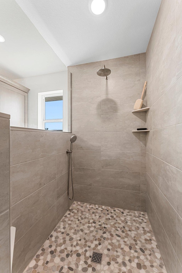 bathroom featuring a tile shower and a textured ceiling