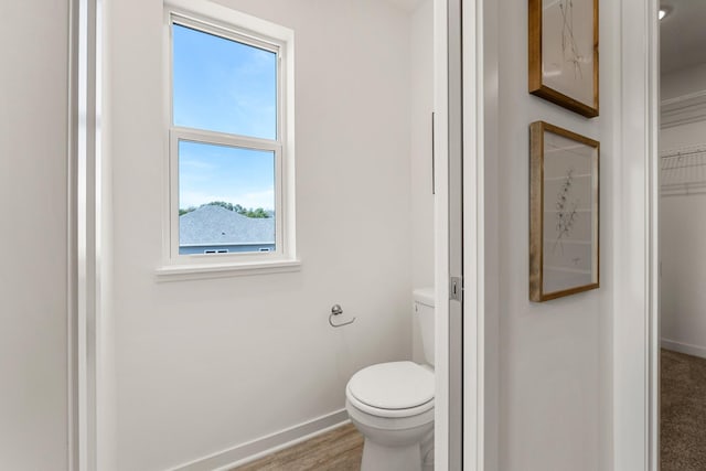 bathroom with hardwood / wood-style flooring, toilet, and a healthy amount of sunlight