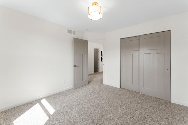 unfurnished bedroom featuring light colored carpet and a closet