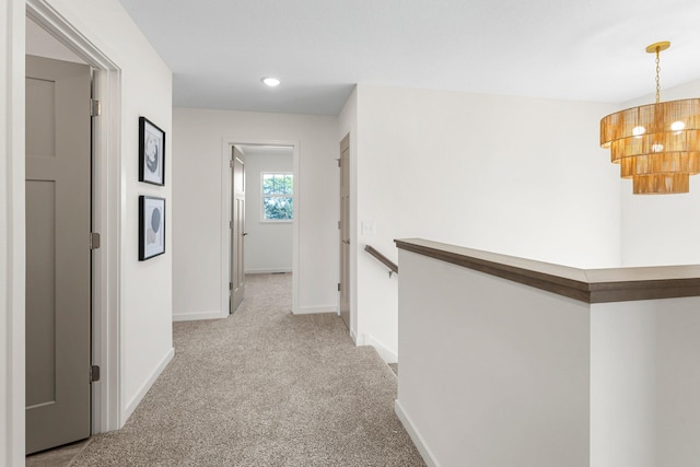 hallway featuring light carpet and a chandelier