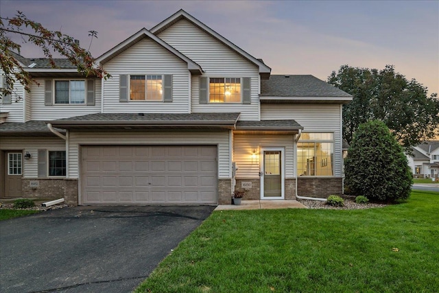 view of front facade with stone siding, driveway, an attached garage, and a yard