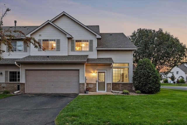 view of front of home featuring a front yard, an attached garage, driveway, and roof with shingles