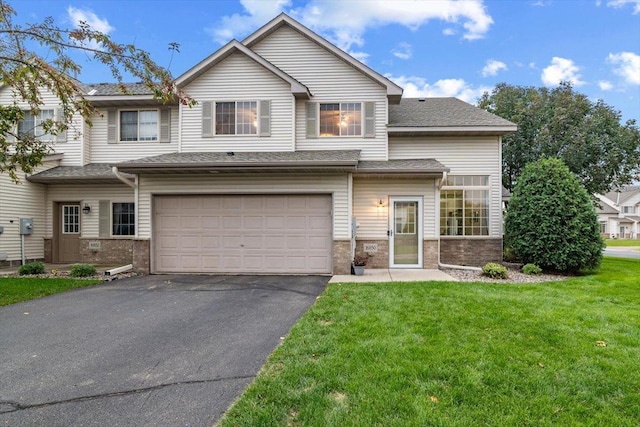 view of front of home featuring brick siding, driveway, an attached garage, and a front lawn