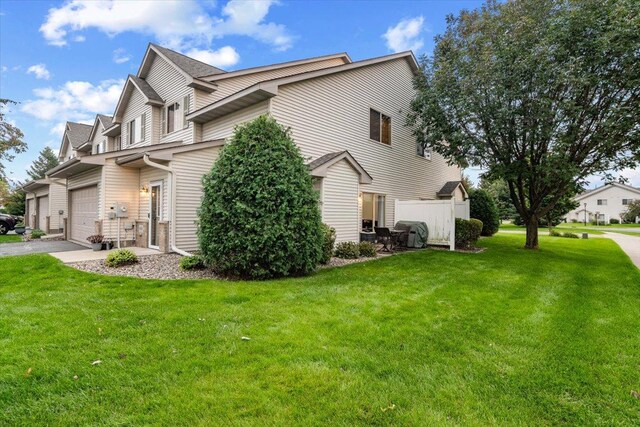 view of side of home featuring aphalt driveway, a lawn, and a garage