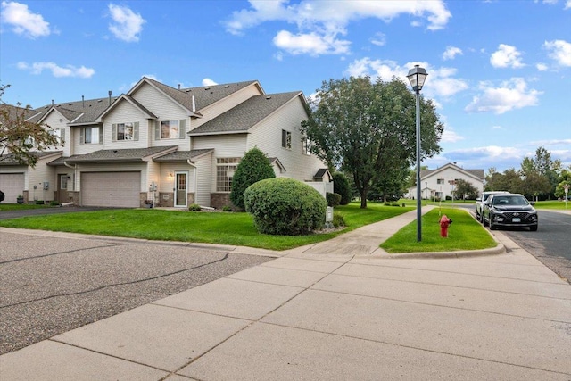 view of front facade with a front lawn, an attached garage, and driveway