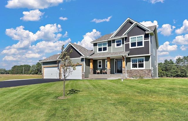 craftsman house featuring aphalt driveway, stone siding, board and batten siding, a front yard, and an attached garage