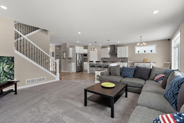 living room featuring baseboards, visible vents, recessed lighting, stairs, and a chandelier