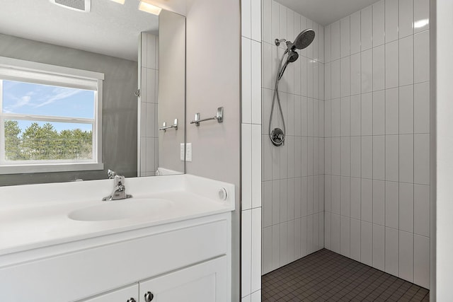 full bathroom with a tile shower and vanity