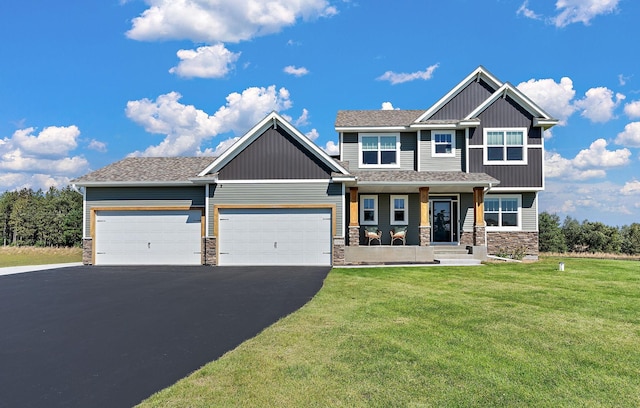 craftsman house featuring a front lawn, a garage, stone siding, and driveway