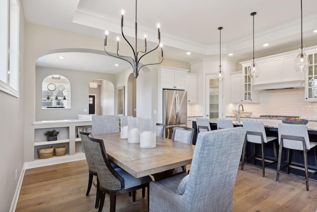 dining area featuring crown molding, a raised ceiling, and light hardwood / wood-style floors