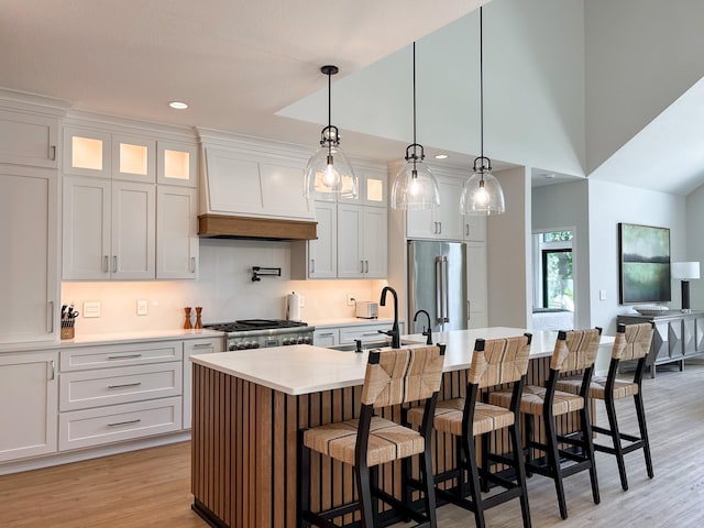 kitchen with a kitchen island with sink, appliances with stainless steel finishes, white cabinetry, and pendant lighting