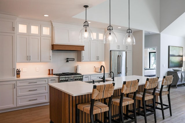 kitchen featuring hanging light fixtures, hardwood / wood-style flooring, stainless steel appliances, and an island with sink