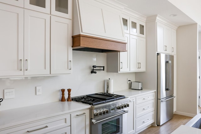 kitchen with light hardwood / wood-style floors, custom exhaust hood, white cabinetry, and high quality appliances