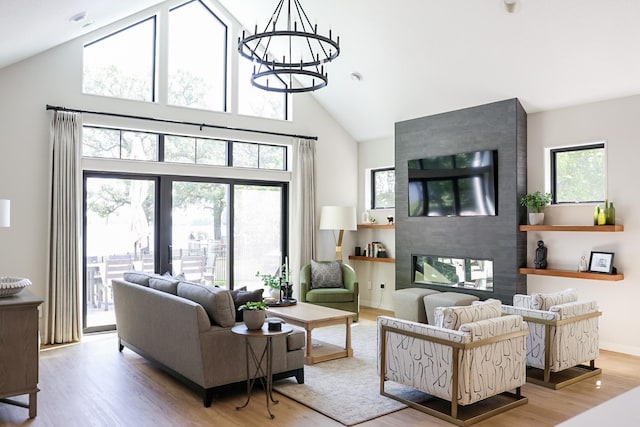 living room featuring a multi sided fireplace, high vaulted ceiling, hardwood / wood-style floors, and a chandelier