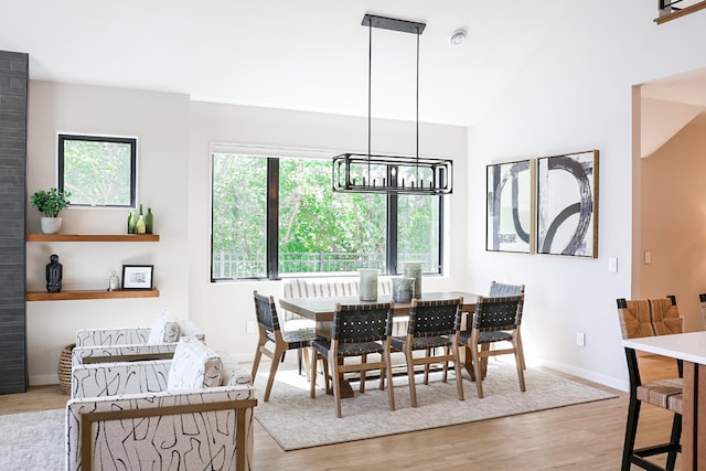 dining room featuring vaulted ceiling, an inviting chandelier, and light hardwood / wood-style floors