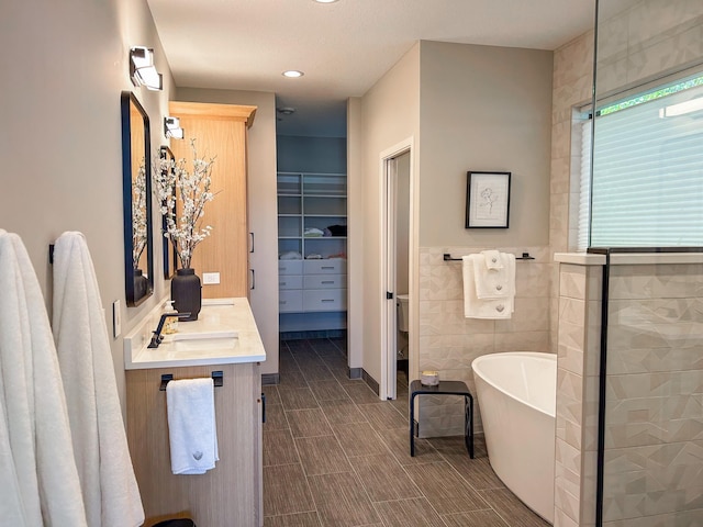 bathroom featuring vanity, a bathtub, and tile walls