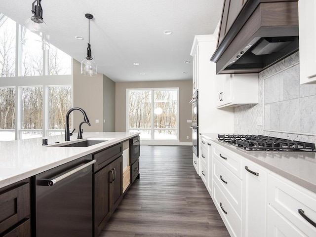 kitchen featuring appliances with stainless steel finishes, sink, custom range hood, and white cabinets