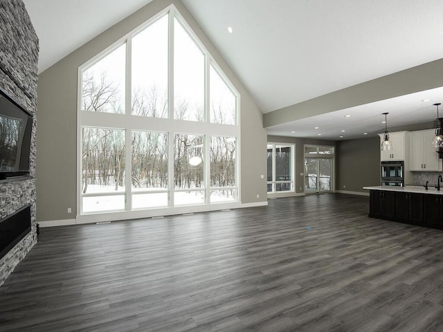 unfurnished living room featuring a fireplace, high vaulted ceiling, and dark hardwood / wood-style floors