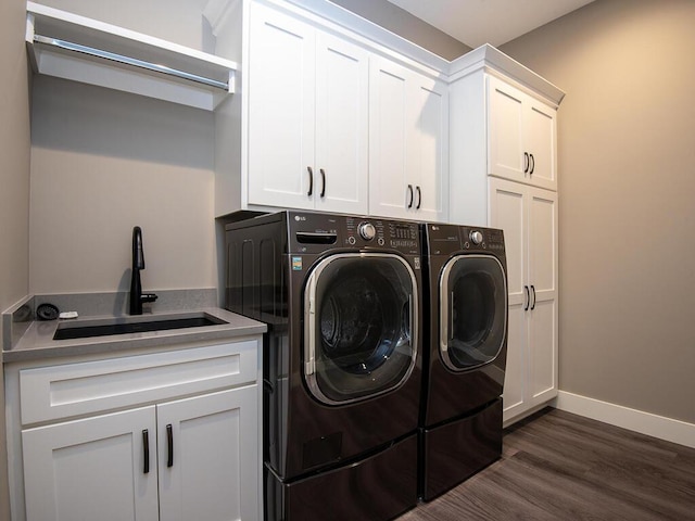 laundry area with sink, dark wood-type flooring, washing machine and dryer, and cabinets