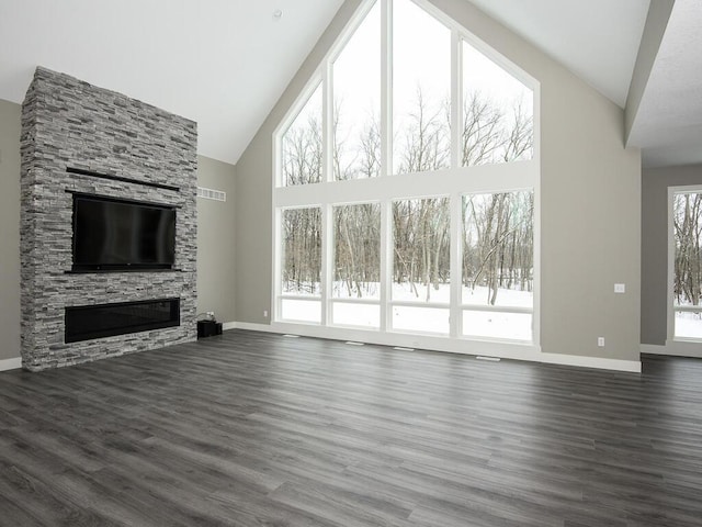 unfurnished living room with dark hardwood / wood-style floors, a stone fireplace, and high vaulted ceiling