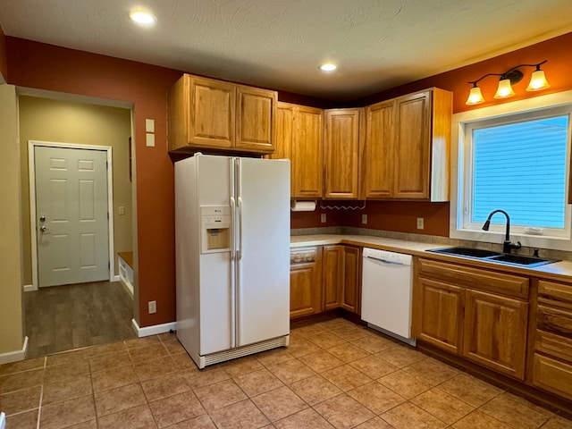 kitchen with white appliances, light hardwood / wood-style floors, a textured ceiling, and sink