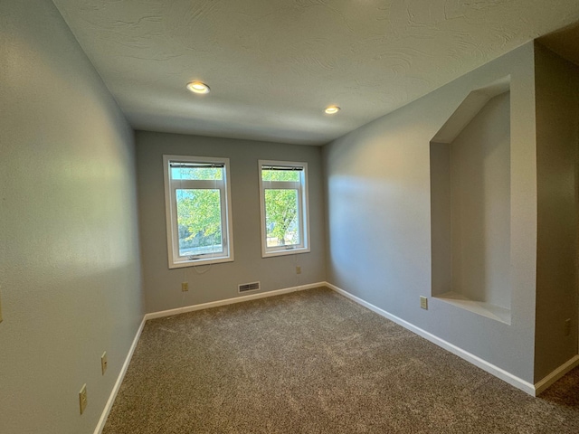 empty room with a textured ceiling and carpet flooring