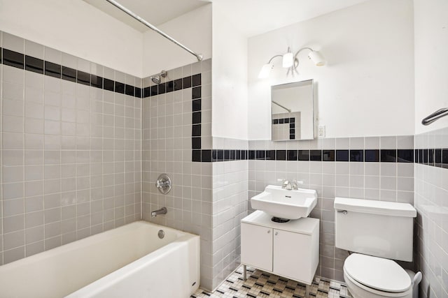 full bathroom featuring tile patterned floors, toilet, tile walls, tiled shower / bath combo, and vanity