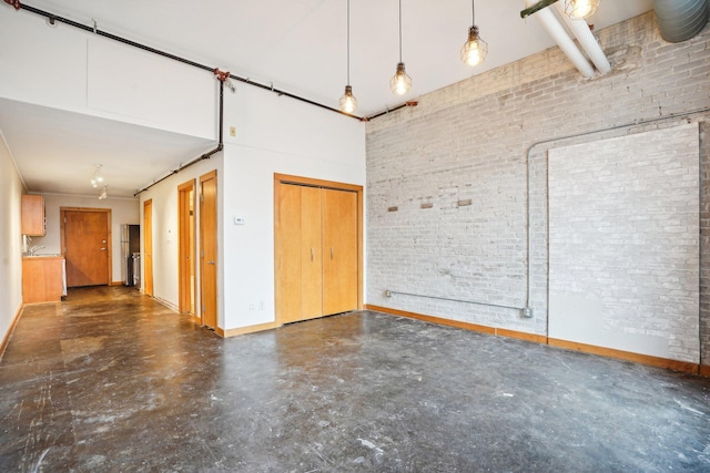 unfurnished room featuring a towering ceiling and brick wall