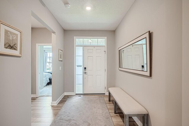 foyer entrance with light hardwood / wood-style floors and a textured ceiling