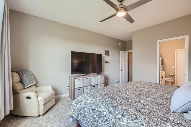 bedroom featuring ceiling fan, light colored carpet, and ensuite bath