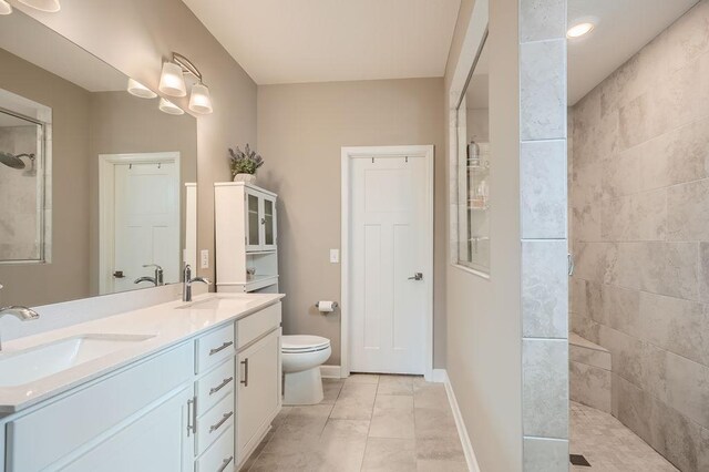 bathroom with vanity, toilet, and a tile shower