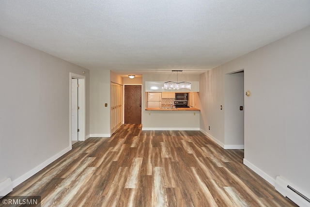 unfurnished living room with a notable chandelier, a baseboard radiator, dark hardwood / wood-style flooring, and a textured ceiling