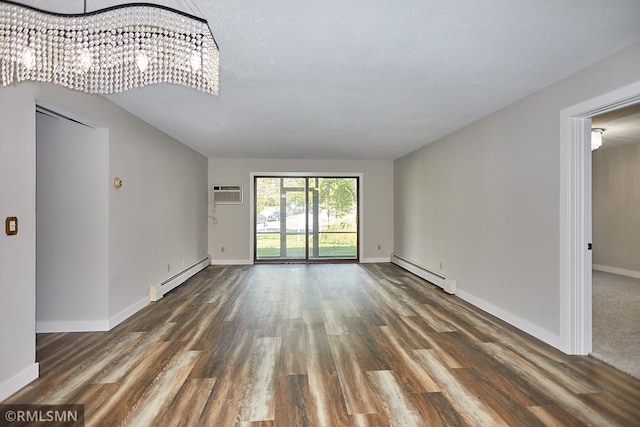 empty room featuring dark wood-type flooring, a baseboard heating unit, and an AC wall unit