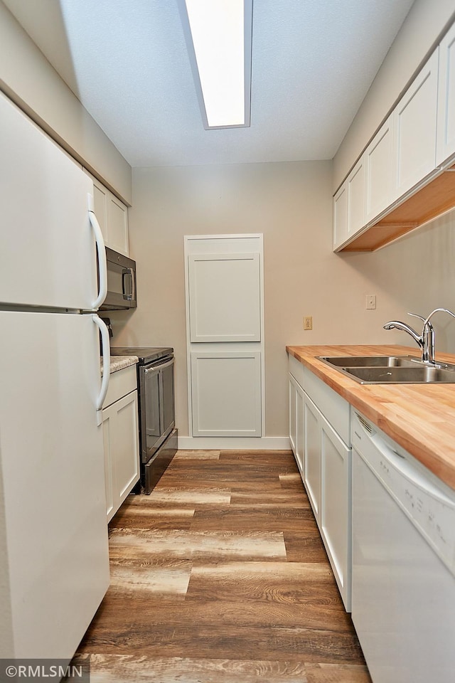 kitchen with light wood-type flooring, sink, white cabinets, butcher block counters, and black appliances