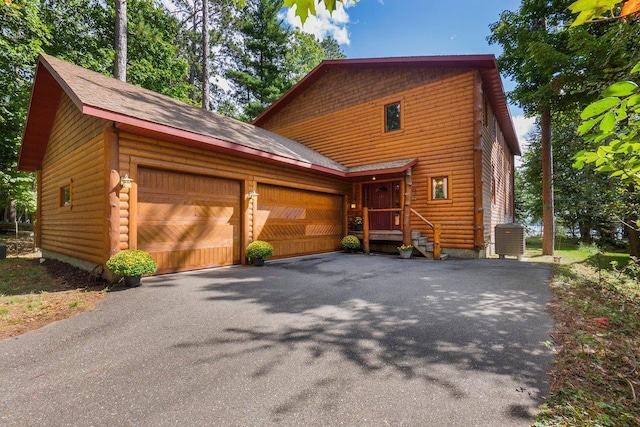 view of front of house with aphalt driveway, cooling unit, and a garage