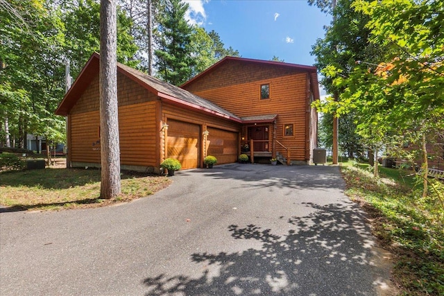 exterior space featuring aphalt driveway, cooling unit, and an attached garage