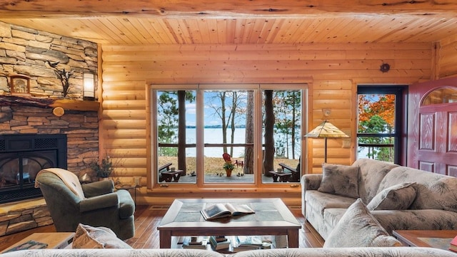 living room with rustic walls, a stone fireplace, wooden ceiling, and wood finished floors