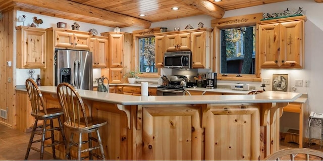 kitchen featuring wood ceiling, stainless steel appliances, beamed ceiling, and light brown cabinetry