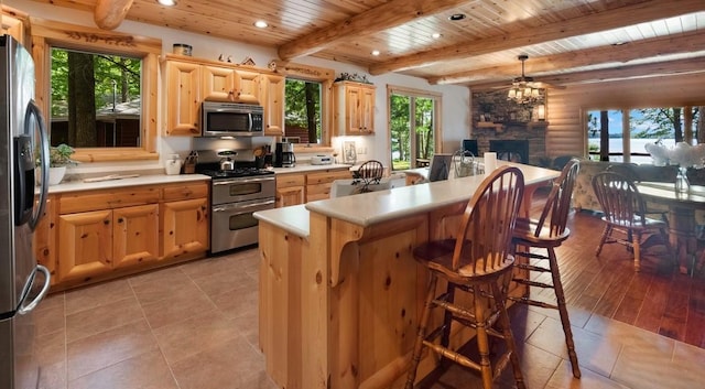 kitchen with light brown cabinets, open floor plan, wood ceiling, light countertops, and appliances with stainless steel finishes