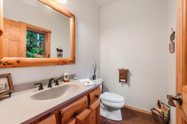 half bath with tile patterned floors, baseboards, toilet, and vanity