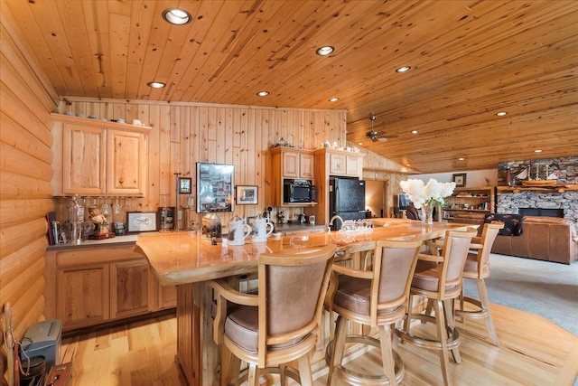 kitchen with light brown cabinets, recessed lighting, black appliances, a kitchen bar, and wooden ceiling