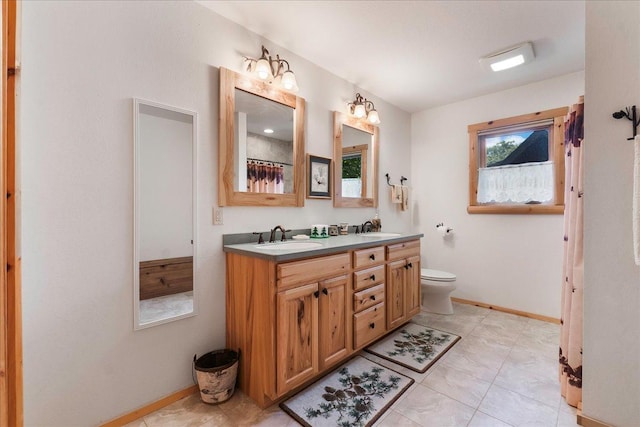 full bathroom featuring double vanity, baseboards, and a sink