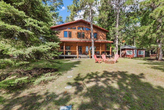 back of house featuring a lawn, an outdoor fire pit, and an outdoor structure