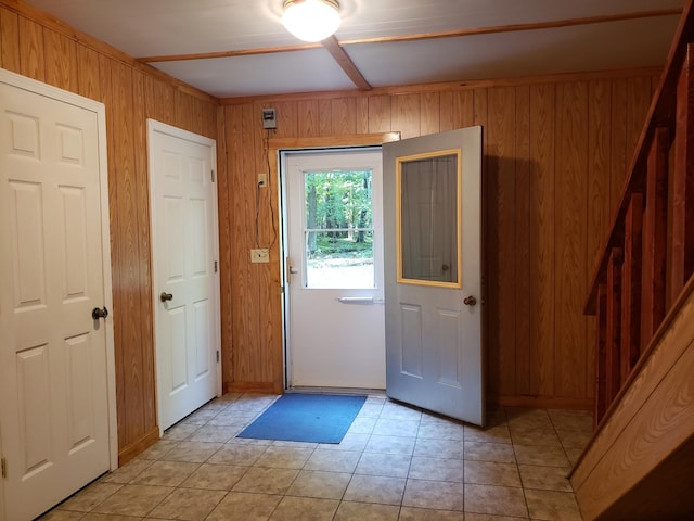 doorway featuring light tile patterned flooring and wood walls