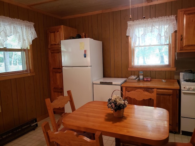 kitchen featuring wooden walls, white appliances, hanging light fixtures, and crown molding