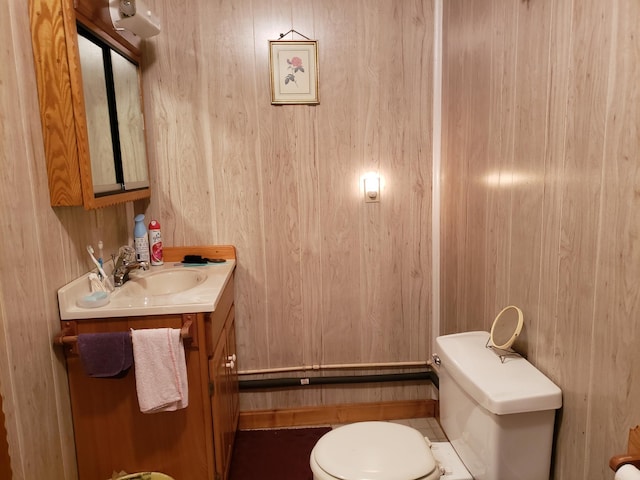 bathroom with vanity, wood walls, and toilet