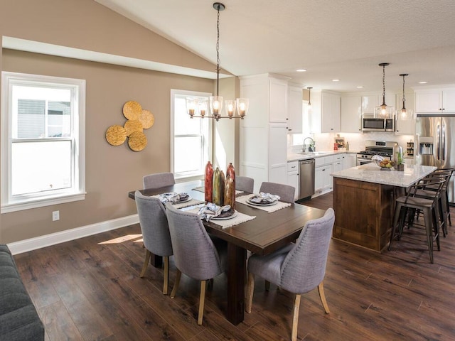 dining room featuring a healthy amount of sunlight, vaulted ceiling, dark hardwood / wood-style floors, and sink