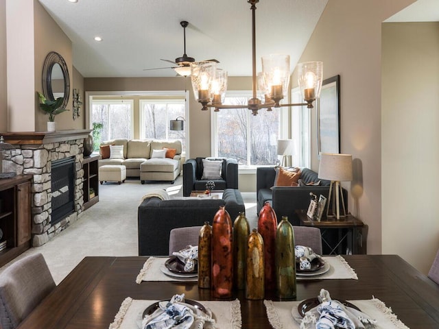 interior space featuring vaulted ceiling, ceiling fan with notable chandelier, and a fireplace