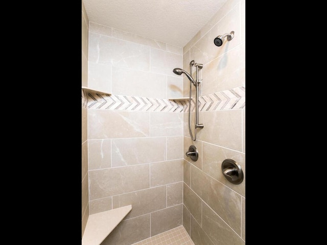 bathroom featuring tiled shower and a textured ceiling