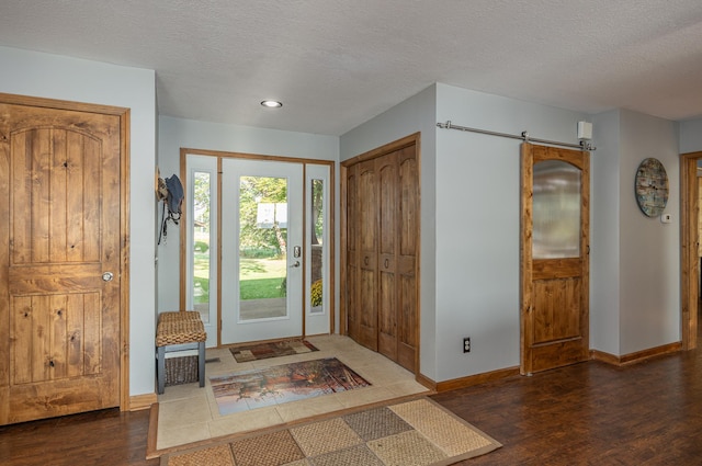 entryway with a textured ceiling, dark wood-type flooring, and a barn door